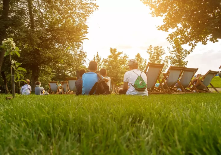 Symbolfoto zu einem Beitrag von 5min.at: Personen sitzen auf einer Wiese neben Liegest&uuml;hlen