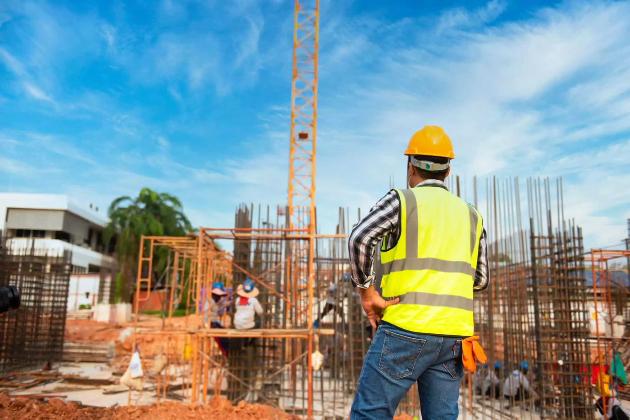 Symbolfoto zu einem Beitrag von 5min.at: Ein Bauarbeiter steht vor einem Kran