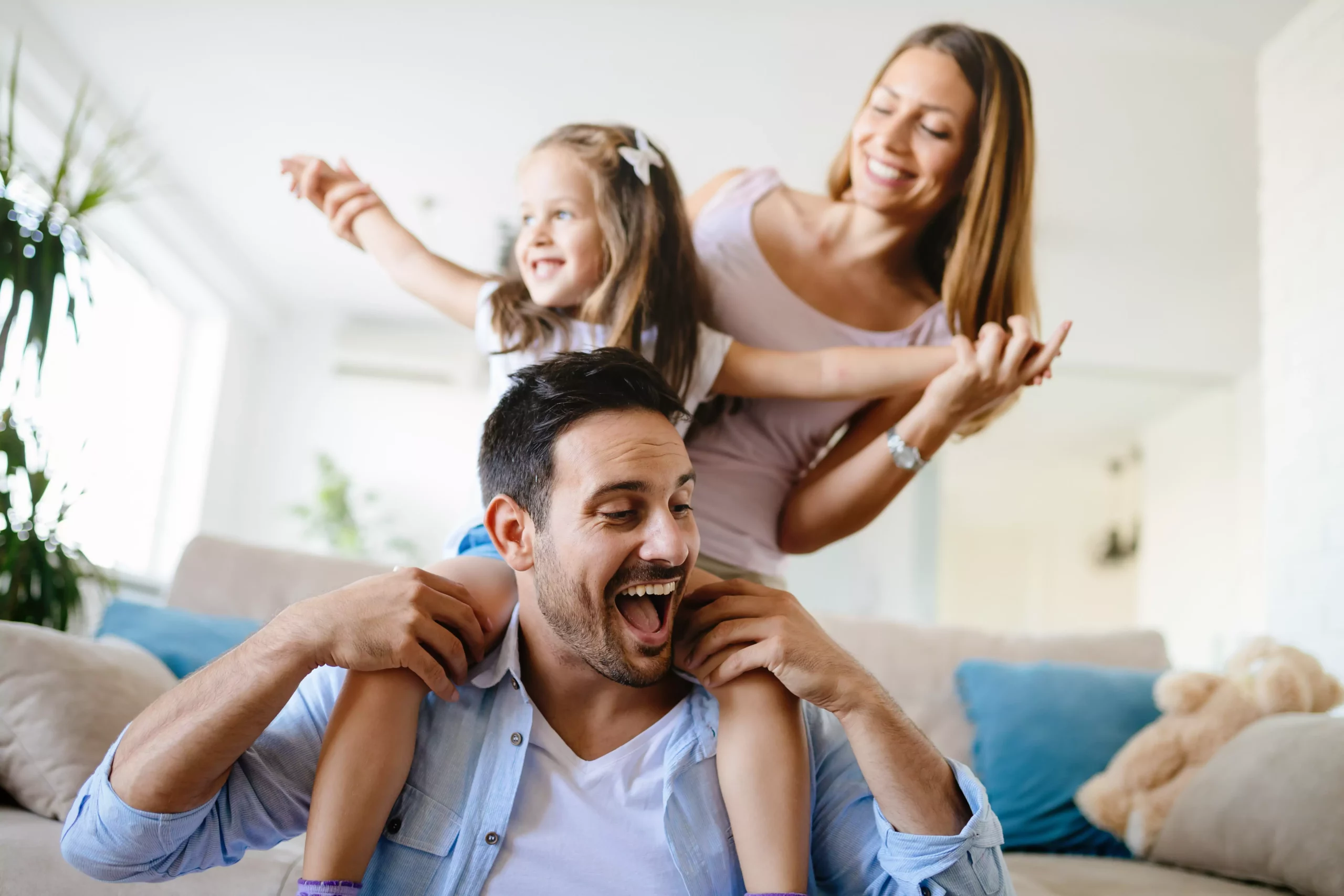 Symbolfoto von 5min.at: Eine glückliche Familie spielt zuhause im Wohnzimmer.
