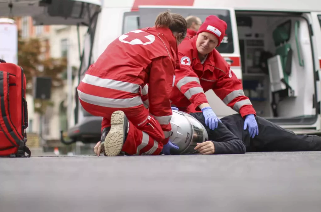 Symbolfoto von 5min.at: Zwei Sanit&auml;ter k&uuml;mmern sich um einen verunfallten Mopedfahrer