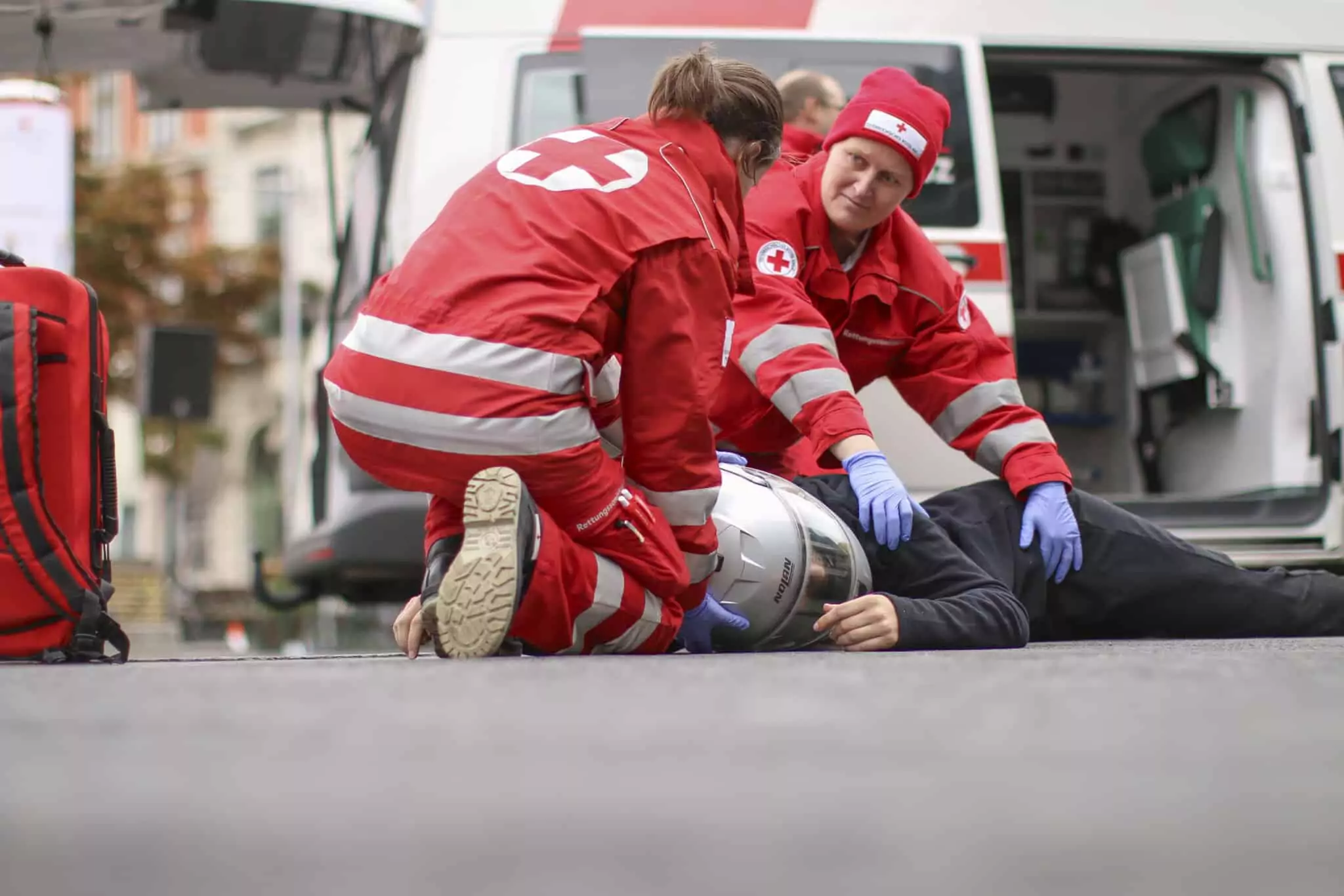 Symbolfoto von 5min.at: Zwei Sanitäter kümmern sich um einen verunfallten Mopedfahrer