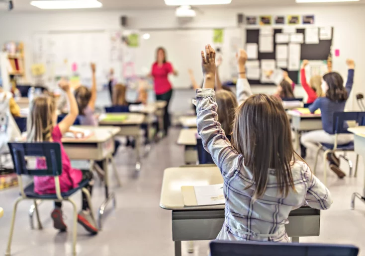 Symbolfoto zu einem Beitrag von 5min.at: Schüler zeigen in der Klasse auf.