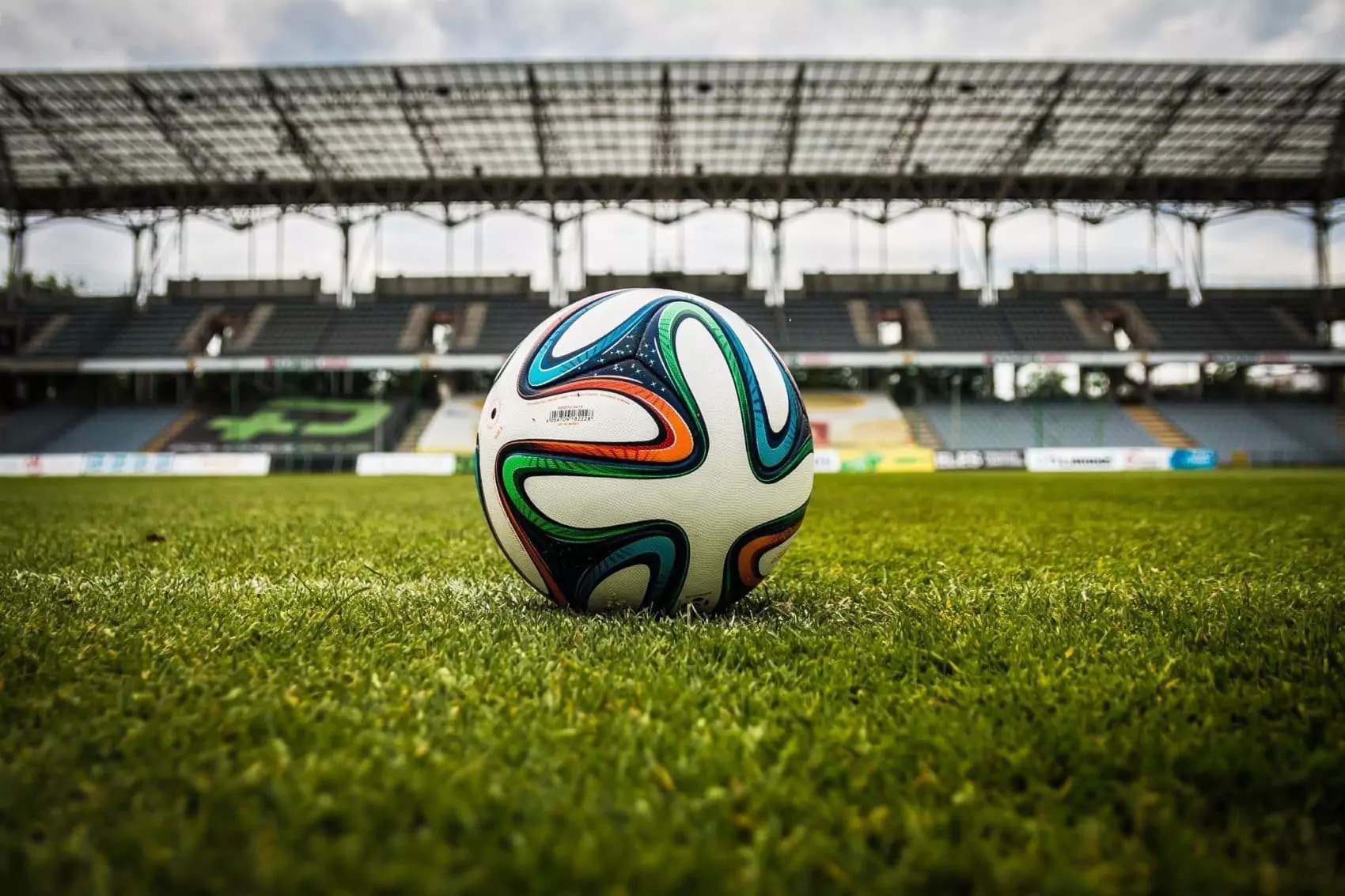 Symbolfoto zu einem Beitrag von 5min.at: Ein Fußball liegt auf dem Rasen in einem Stadion