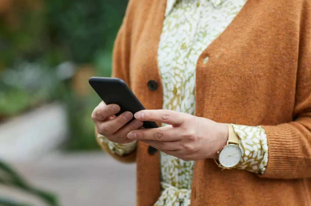 Symbolfoto zu einem Beitrag von 5min.at: Eine ältere Dame hält ein Handy in der Hand.
