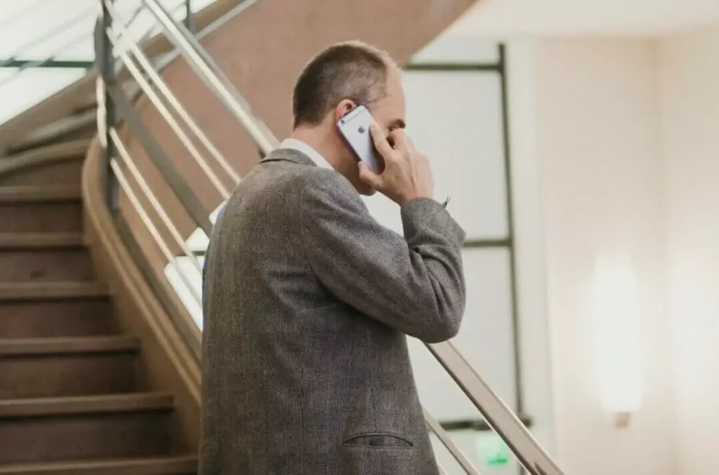 Symbolfoto zu einem Beitrag von 5min.at: Ein Mann im Anzug steht vor einer Treppe und telefoniert