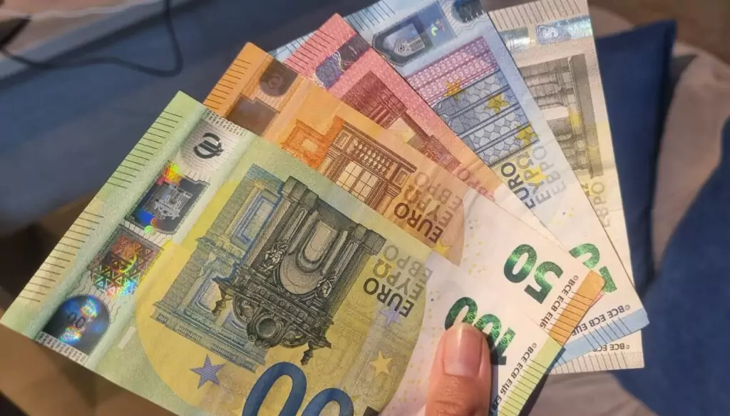 Symbolfoto von 5min.at: Frau hält verschiedene Geldscheine in der Hand.