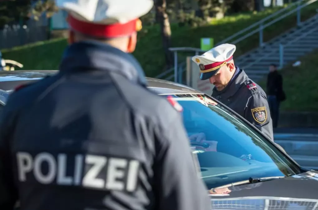 Symbolfoto von 5min.at: Polizisten kontrollieren den Führerschein eines Autofahrers.