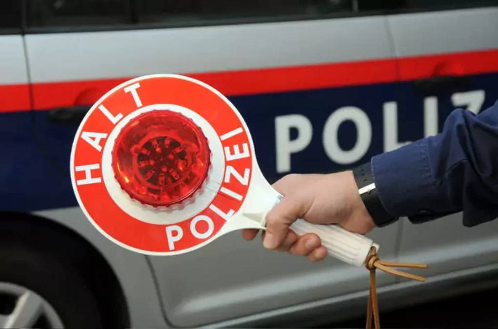 Symbolfoto von 5min.at: Polizist hält ein Halteschild in der Hand.