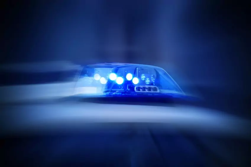 Symbolfoto von 5min.at: Polizeiauto mit eingeschaltetem Blaulicht bei Nacht.