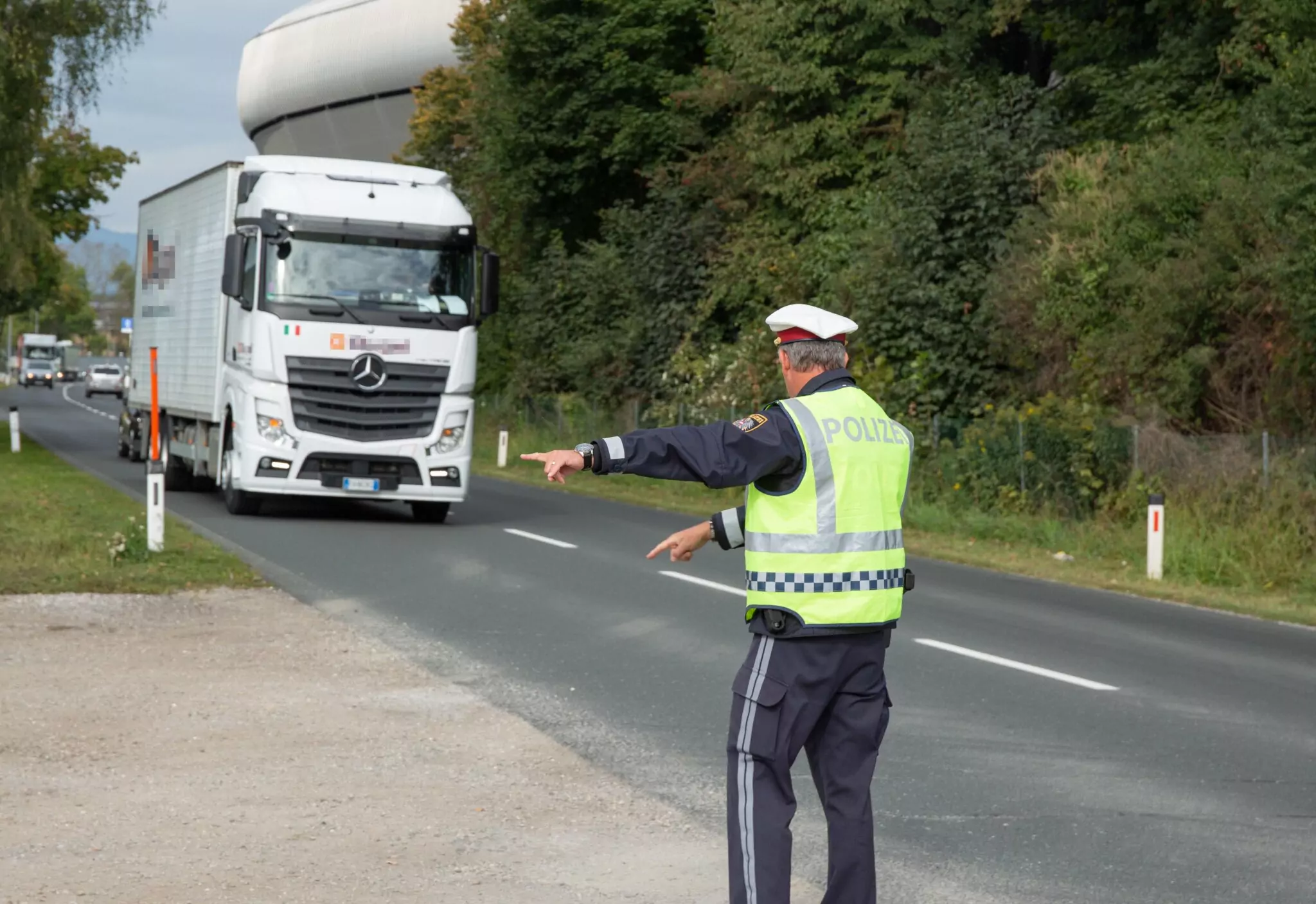Symbolfoto zu einem Beitrag von 5min.at: Ein Polizist kontrolliert einen LKW