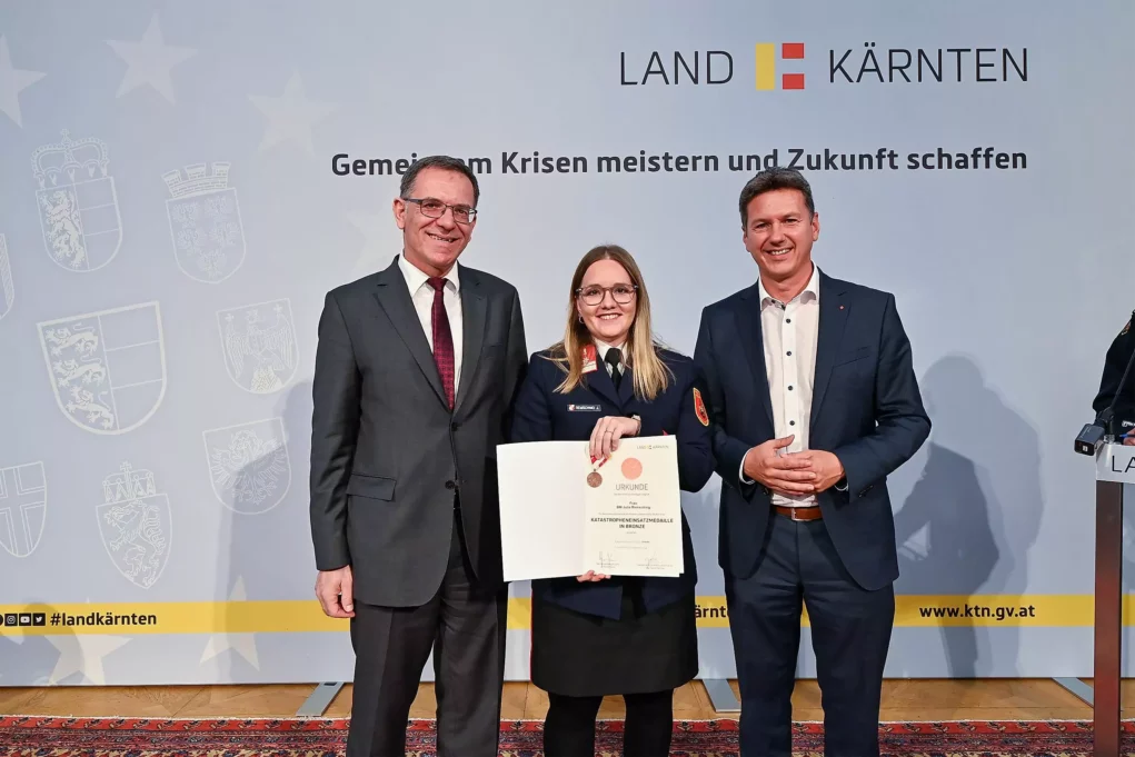 Ein Bild auf 5min.at zeigt eine Feuerwehrfrau und Landesrat Daniel Fellner bei der Verleihung der Kärntner Katastropheneinsatzmedaille.
