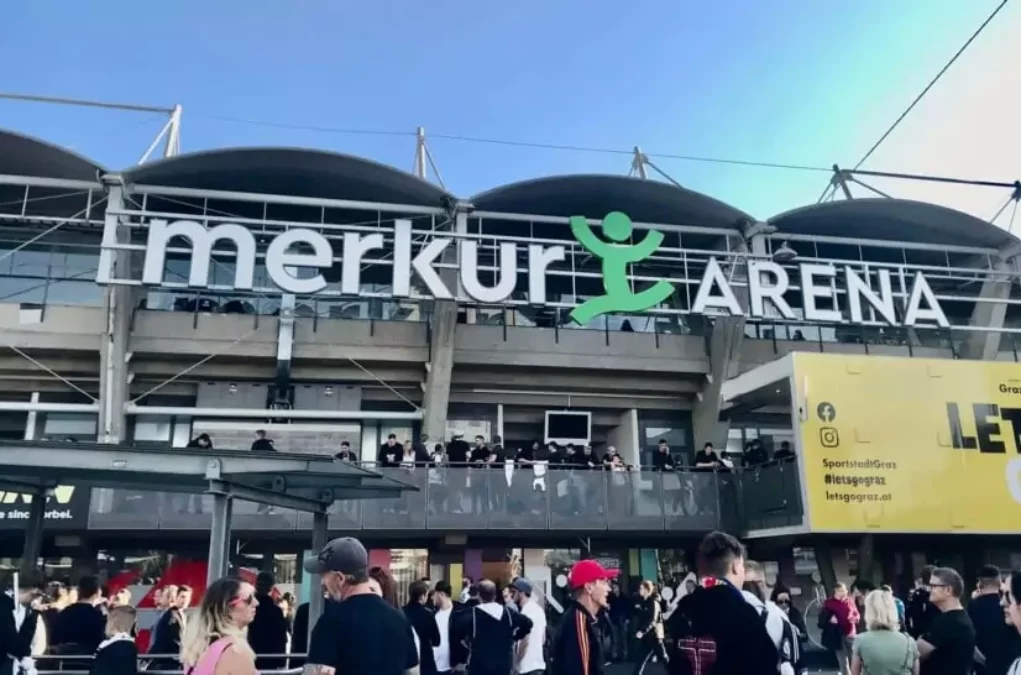 Foto in Beitrag von 5min.at: Zu sehen ist die Merkur Arena bei sch&ouml;nem Wetter und blauem Himmel. Viele Menschen warten davor auf den Einlass.