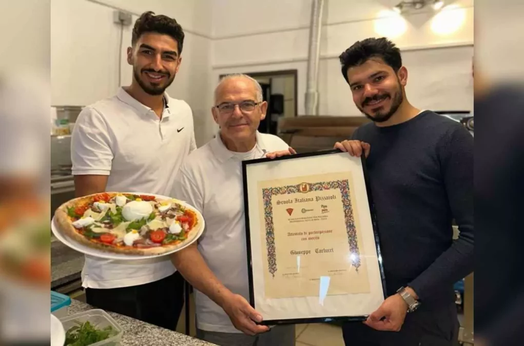 Bild in Beitrag von 5min.at: Zu sehen sind drei Männer, einer von ihnen hält eine Pizza, die beiden anderen eine Urkunde.