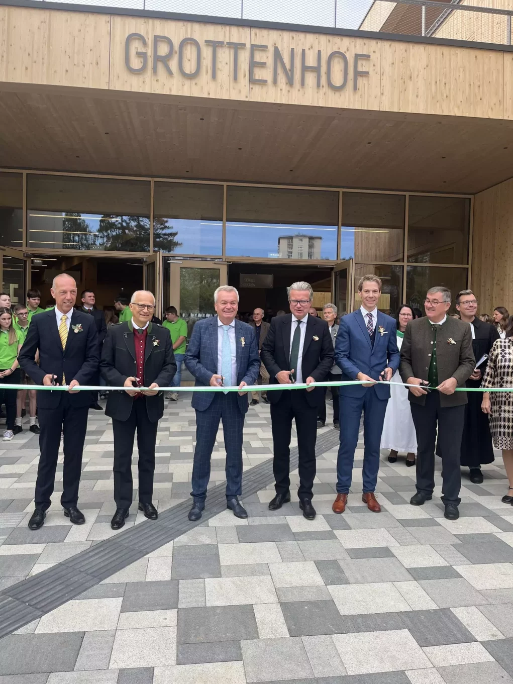 Zu sehen sind sechs Männer in Anzug vor einem Gebäude