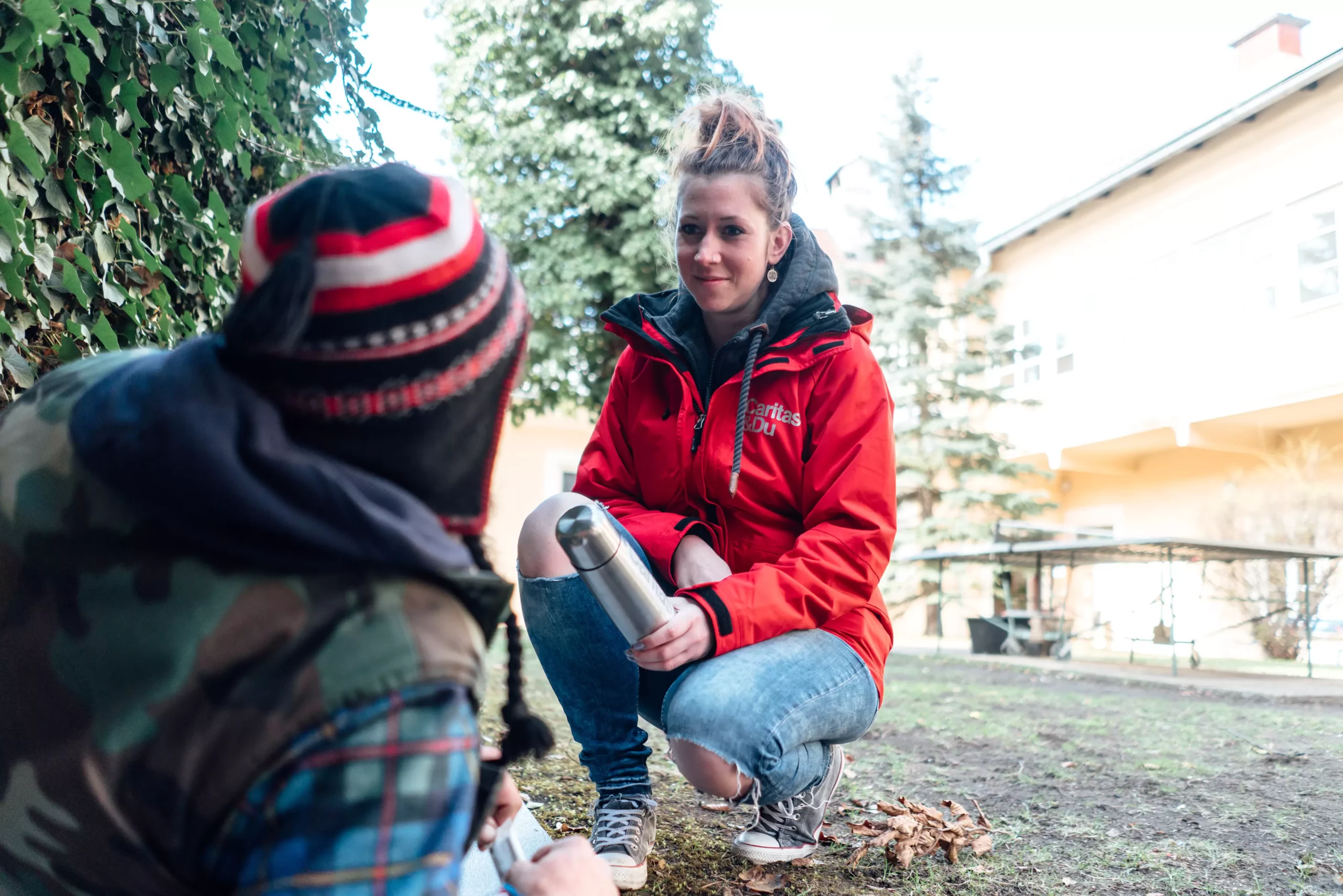 Foto in Beitrag von 5min.at: Eine Frau hilft einem Obdachlosen