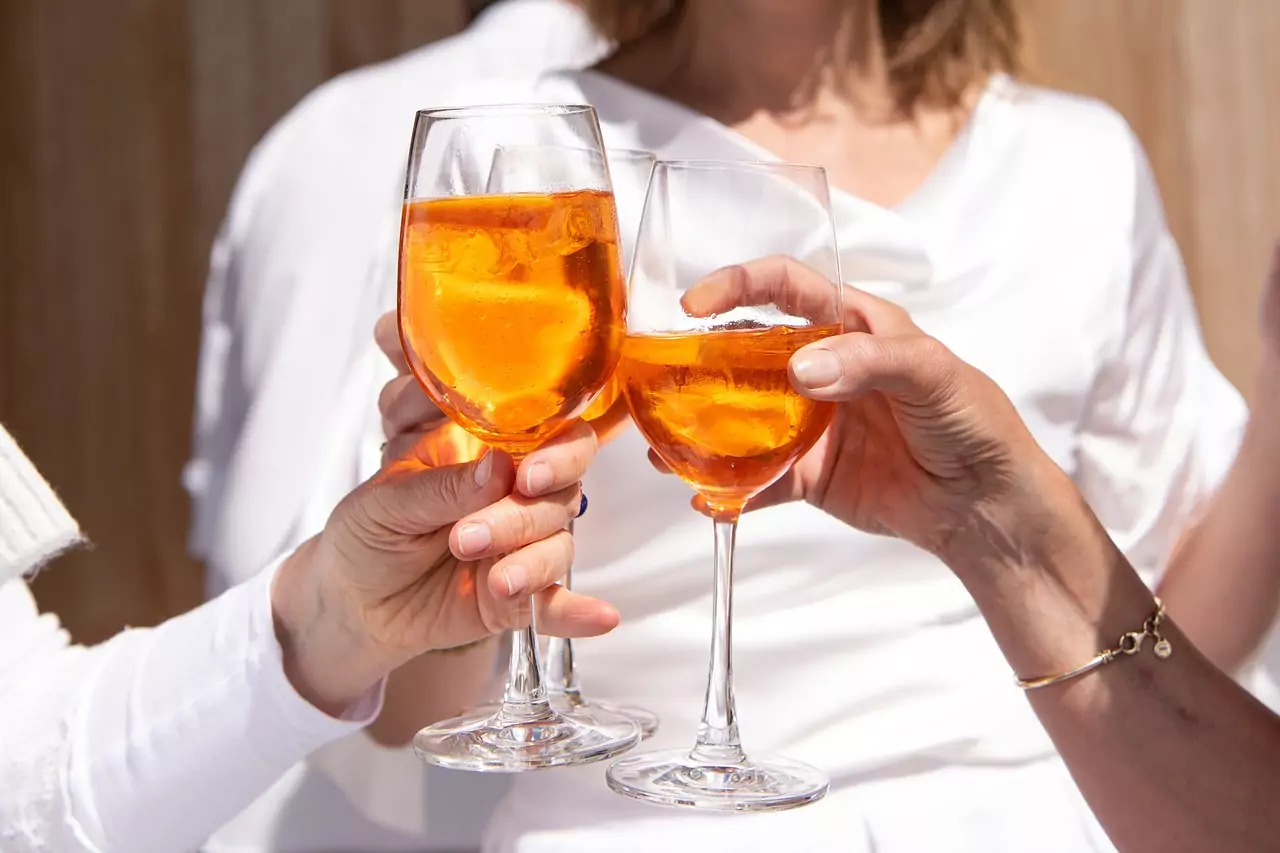 Symbolfoto: Personen beim Aperitivo. Sie stoßen mit den Gläsern an.