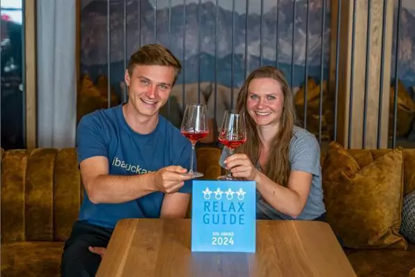 Ein Bild auf 5min.at zeigt Emanuel und Anna Berger, die mit einem Glas Wein auf die Auszeichnung anstoßen.