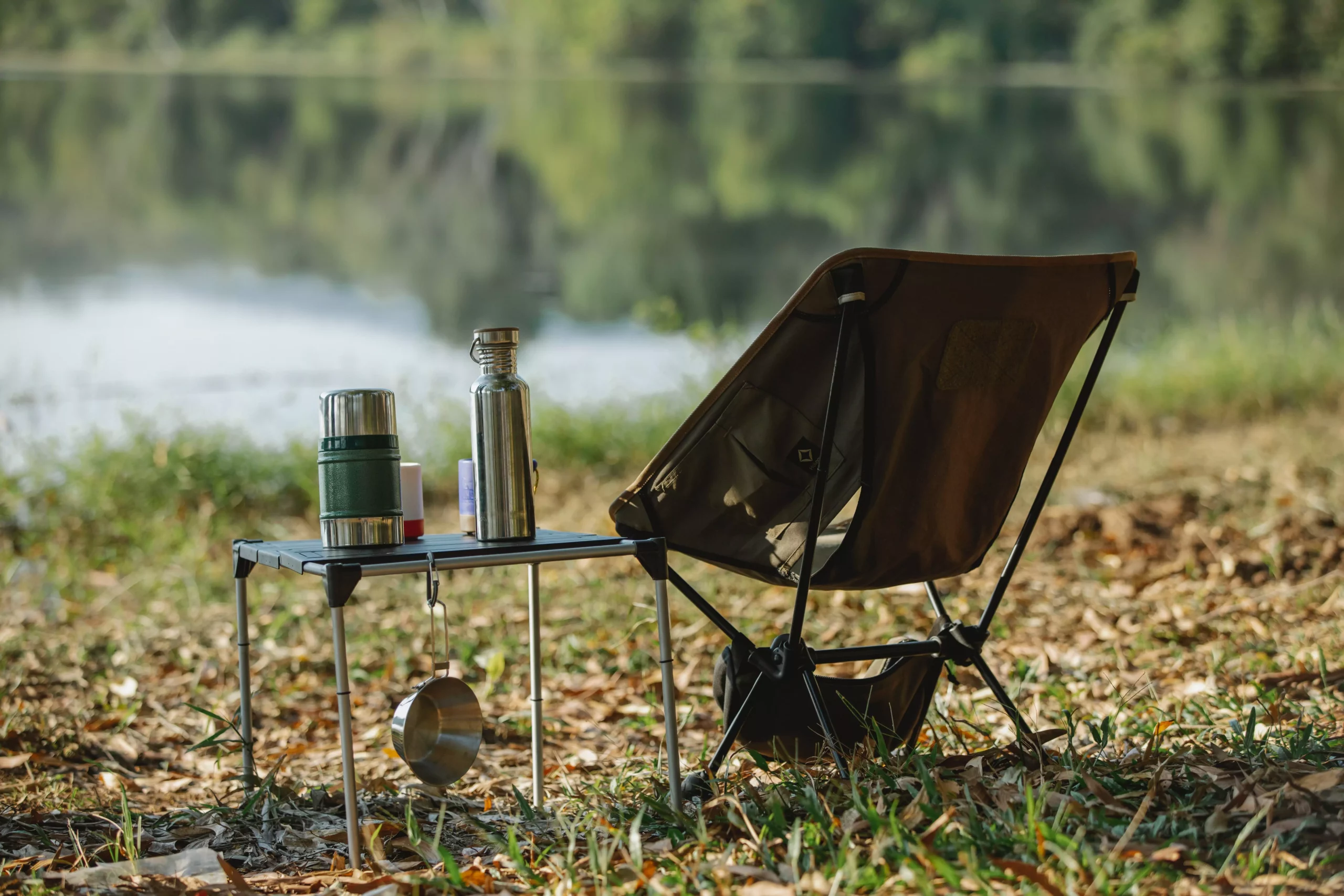 Ein Bild auf 5min.at zeigt einen Campingstuhl sowie ein kleines Tischchen mit Kaffeekanne, welches vor der Kulisse eines Sees aufgestellt wurde.