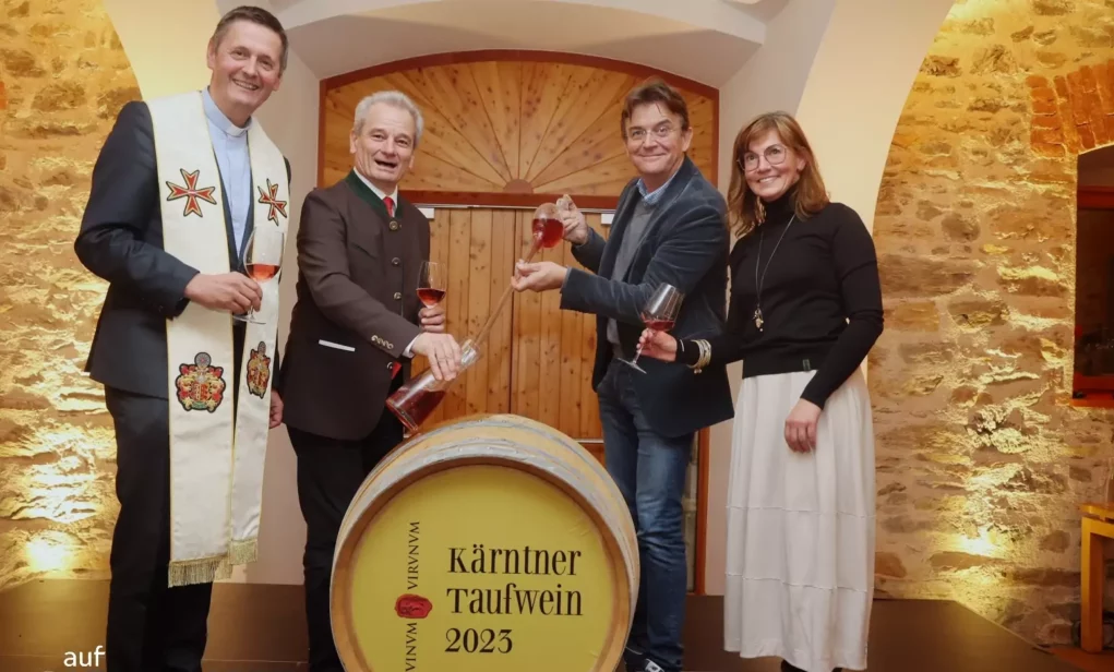 Foto auf 5min.at zeigt ein Gruppenfoto von Sommeliers und einen Dompfarrer bei einer Weintaufe.