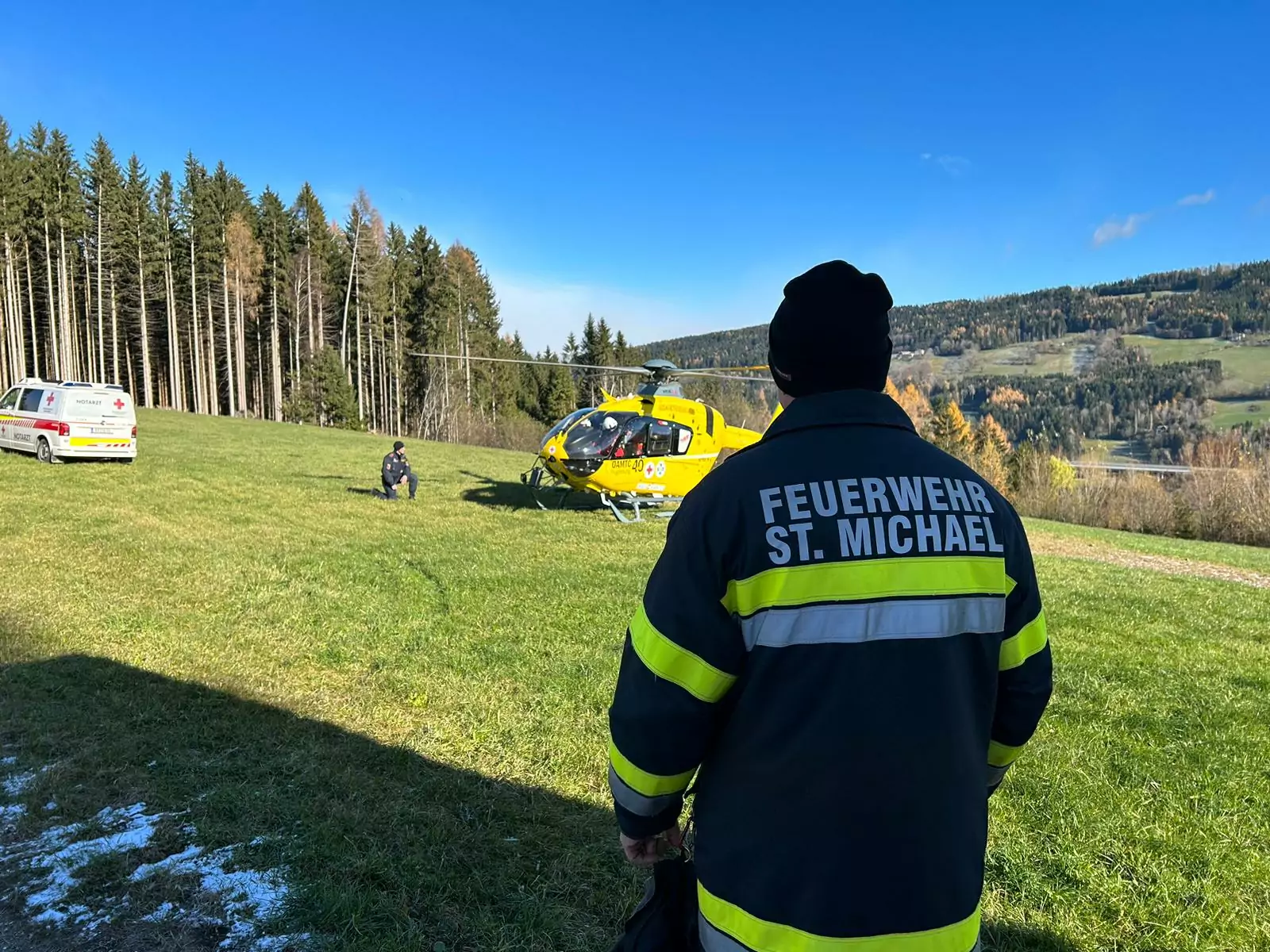 Foto in Beitrag von 5min.at: Zu sehen ist ein Feuerwehrler, der in Richtung des Rettungshubschraubers schaut.