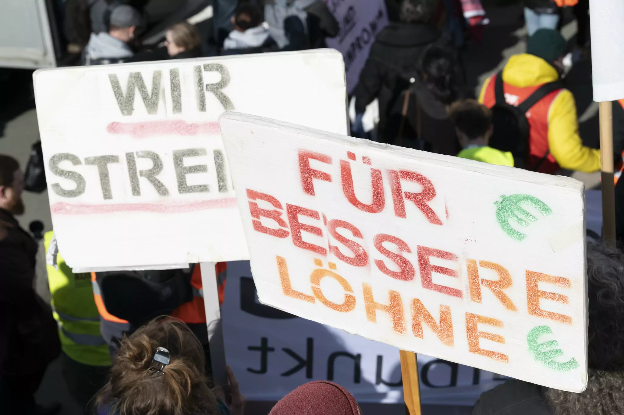 Bild auf 5min.at zeigt eine große Menschenmenge beim Streiken, im Fokus zwei Schilder.