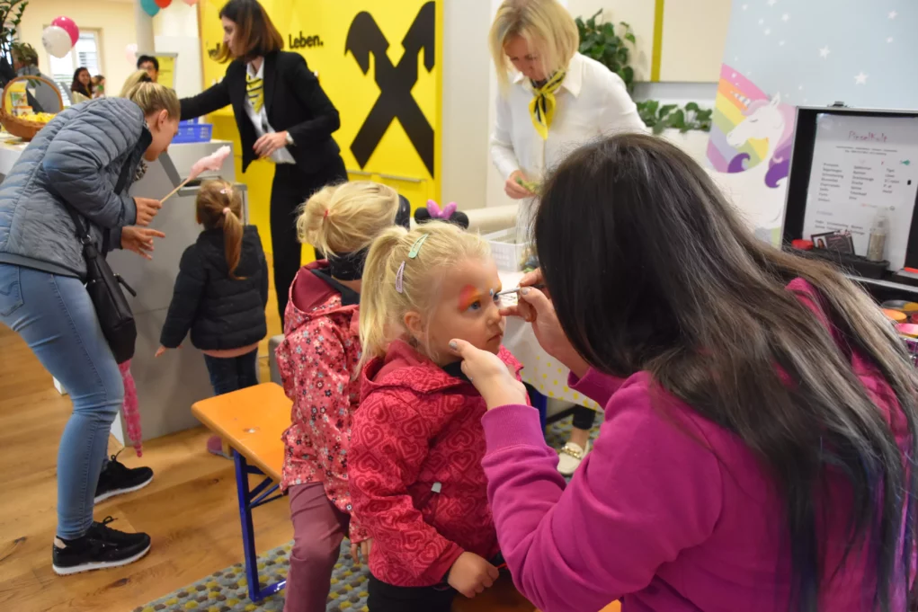 Ein Bild auf 5min.at zeigt eine Frau, die ein M&auml;dchen auf der Veranstaltung der Raiffeisenbank Eberndorf schminkt.
