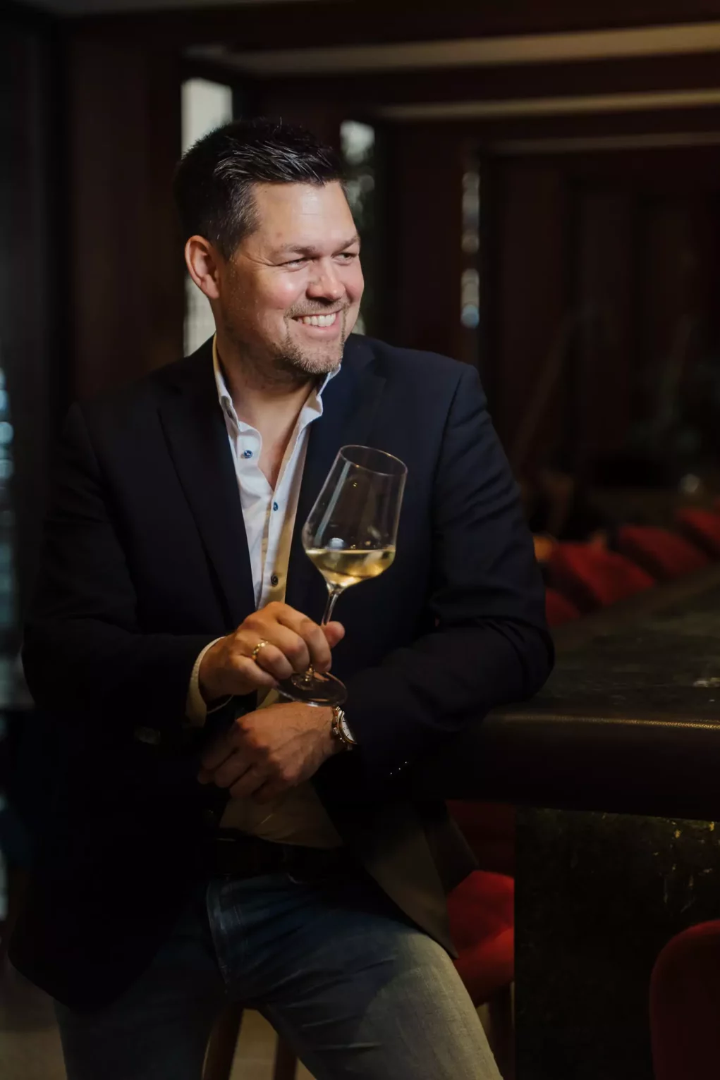 Foto auf 5min.at zeigt einen Grazer Gourmet an einer Bar stehend. Er hält lächelnd ein Weinglas in der Hand.