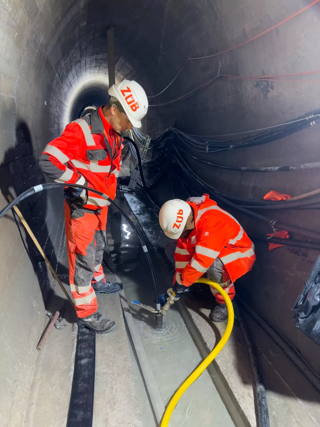 Foto auf 5min.at zeigt Arbeiter in einem Tunnelsystem unter einem Wasserdamm.