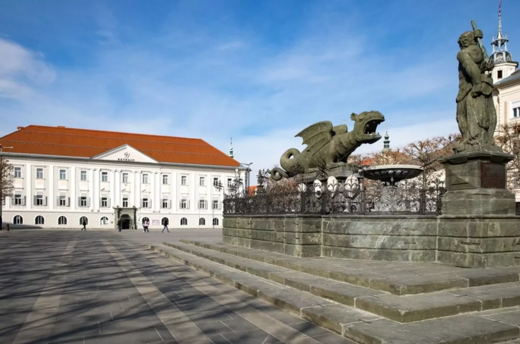 Ein Bild auf 5min.at zeigt den Klagenfurter Lindwurm am Neuen Platz. Dahinter steht das Rathaus.