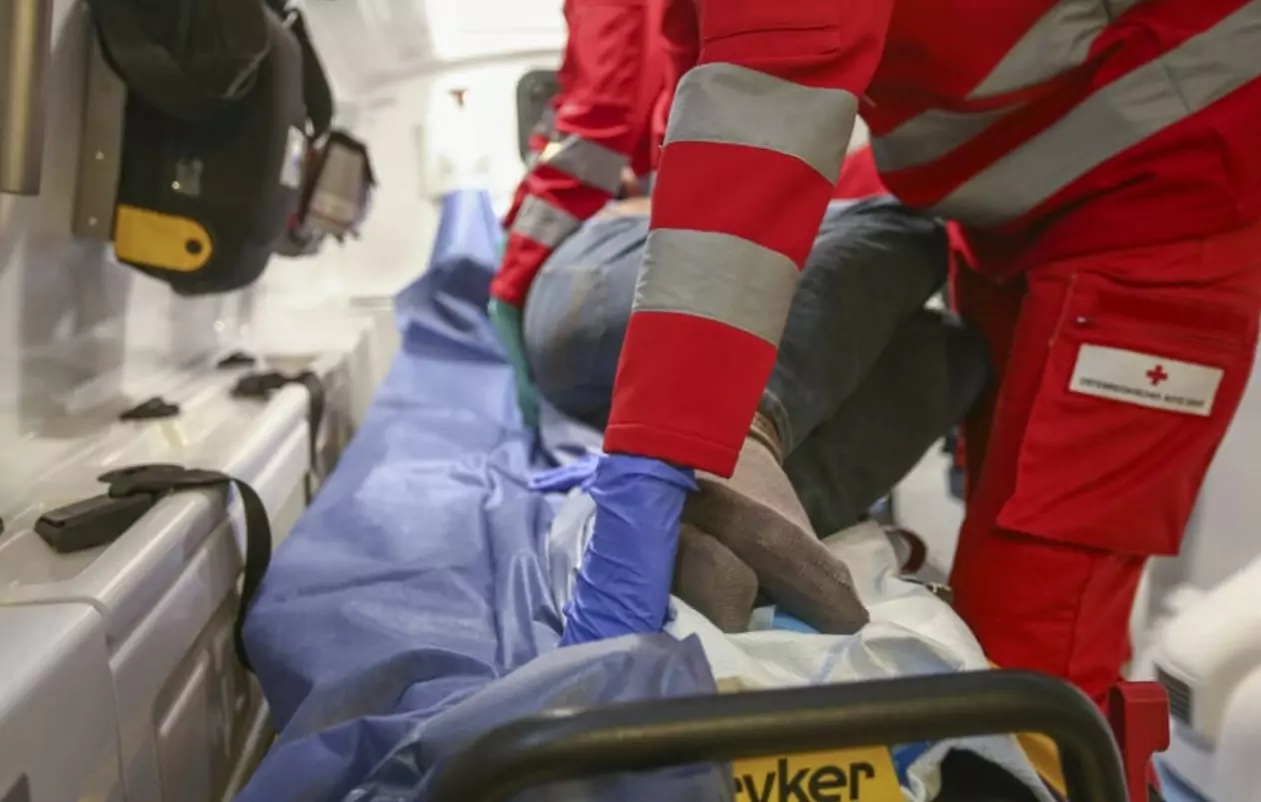 Ein Bild auf 5min.at zeigt einen Rettungssanitäter, der eine Verletzte in einem Rettungswagen verarztet. Die Frau befindet sich in einer stabilen Seitenlage.