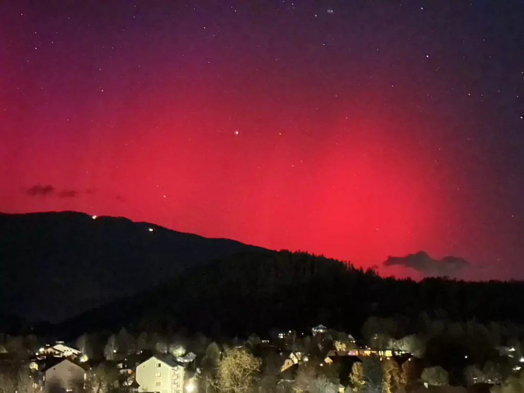 Ein Bild auf 5min.at zeigt pinkfarbene Polarlichter, die am Nachthimmel leuchten.
