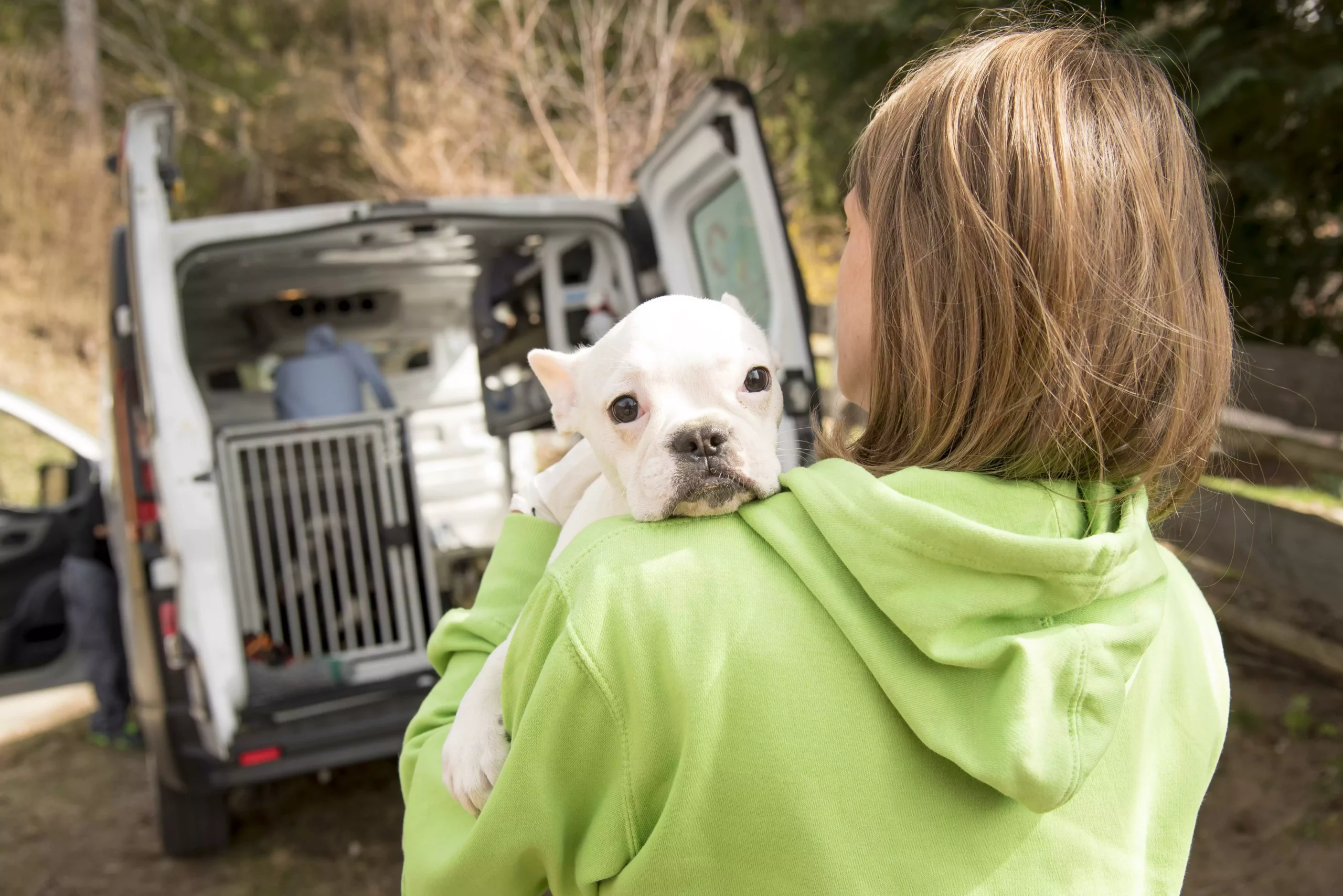Foto auf 5min.at zeigt eine anonyme Frau, die einen Hund trägt. Die Hund sieht über die Schulter der Frau.