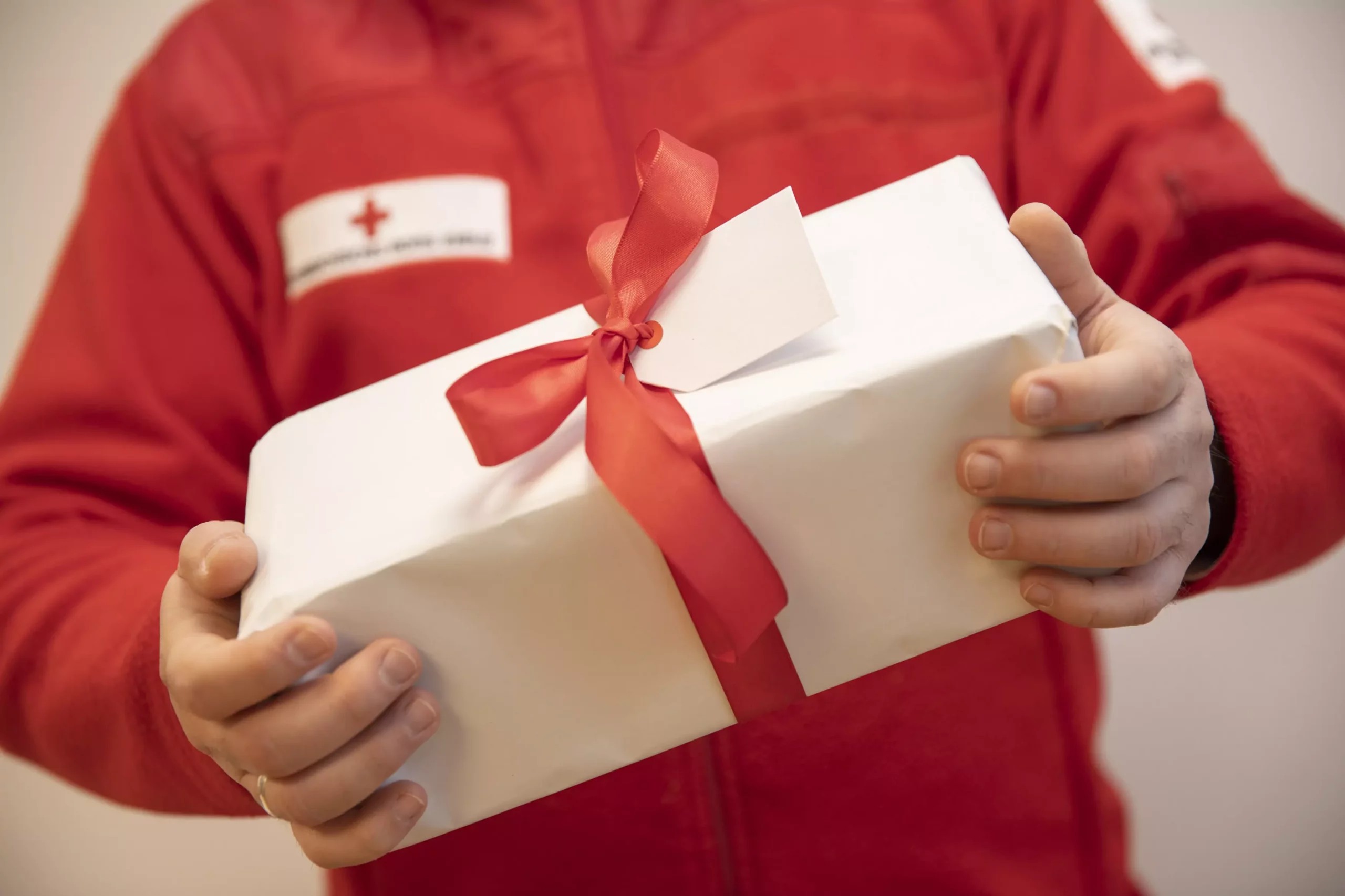 Foto in Beitrag von 5min.at: Zu sehen ist ein Rot-Kreuz-Mann mit einem Paket in der Hand.