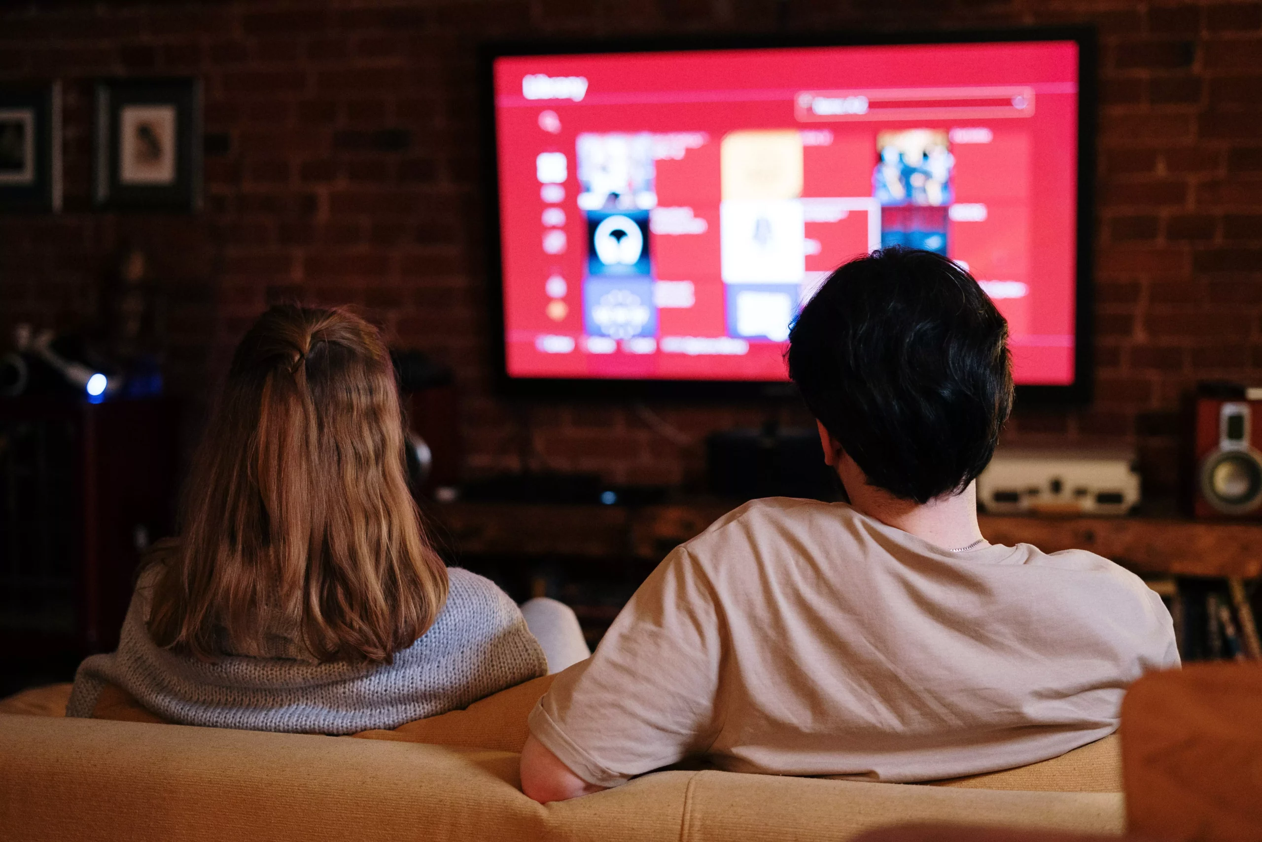 Foto in Beitrag von 5min.at: Zu sehen sind zwei Personen auf einer Couch, die fernsehen.