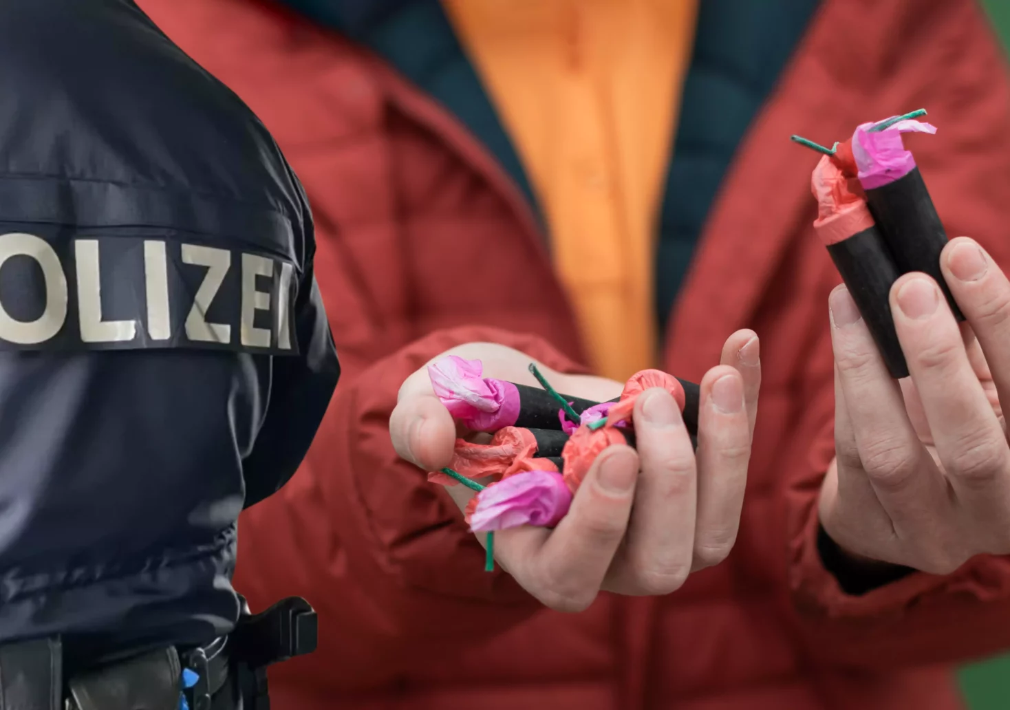 Ein Bild auf 5min.at zeigt einen Polizeibeamten und jemanden, der Böller in den Händen hält.