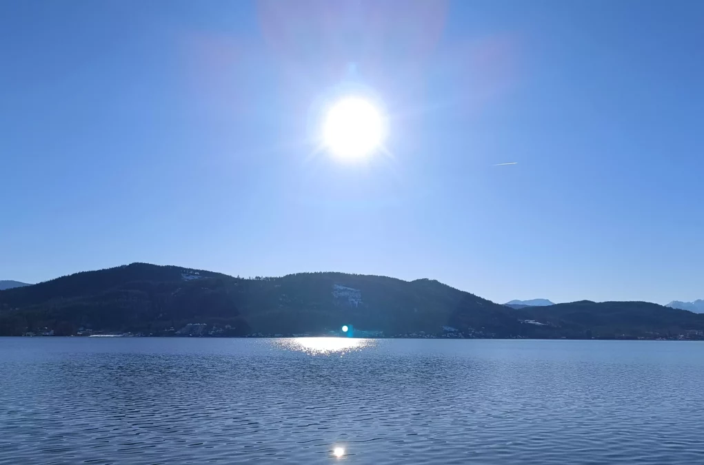 Ein Bild auf 5min.at zeigt das blaue Wasser des Wörthersees im Winter. Der Himmel ist strahlend blau, die Sonne scheint.
