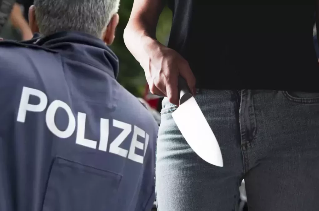 Bild auf 5min.at zeigt ein Polizist und eine Frau mit einem Messer in der Hand.