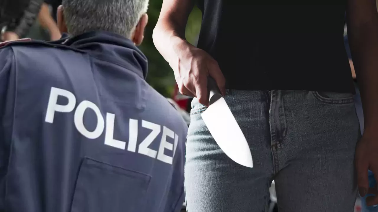 Bild auf 5min.at zeigt ein Polizist und eine Frau mit einem Messer in der Hand.