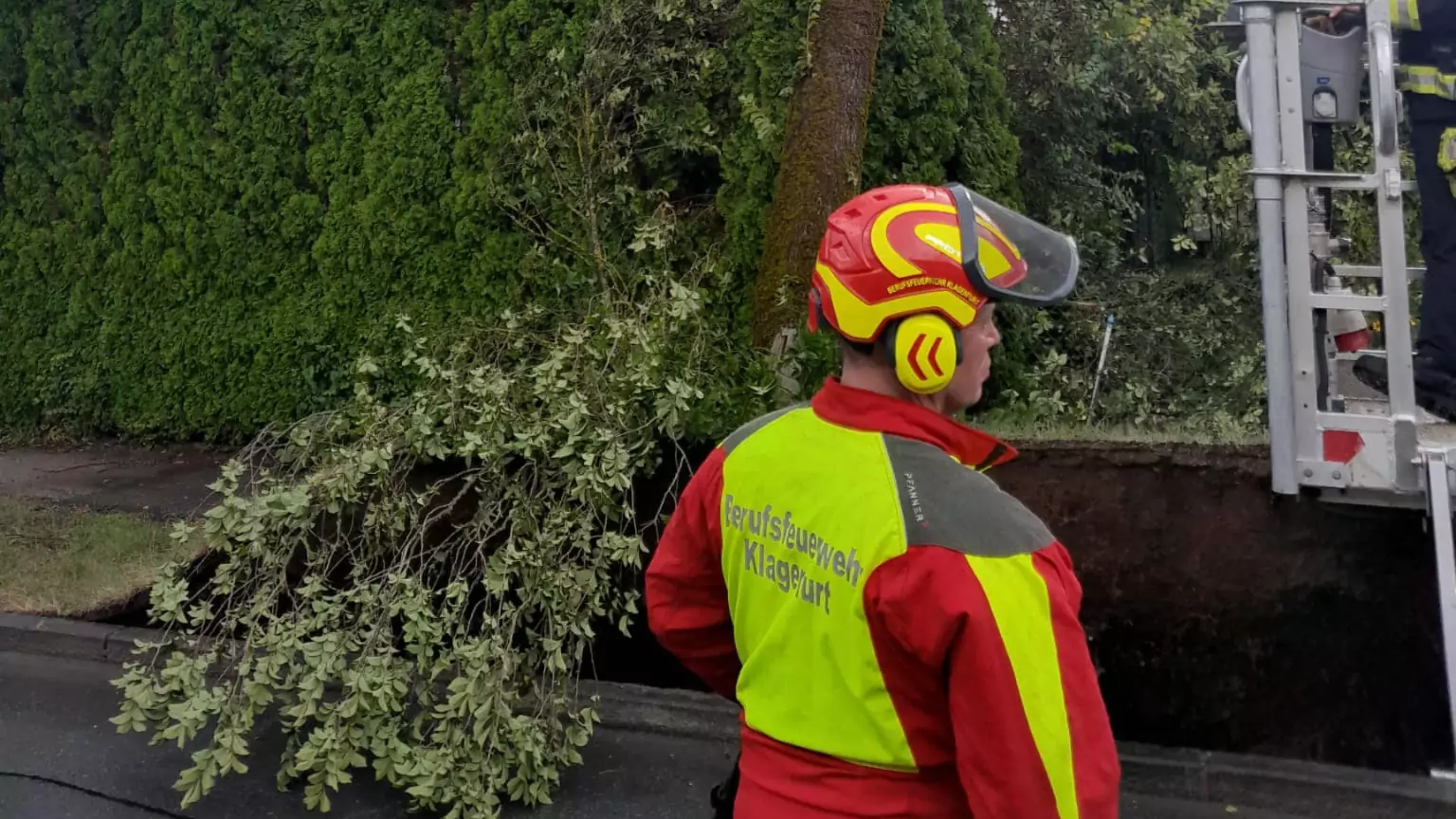 Das Bild auf 5min.at zeigt einen Baum der auf ein Haus gekippt ist und die Feuerwehr.