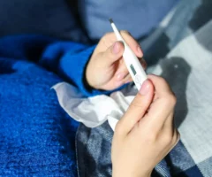 Ein Bild zeigt Frauenh&auml;nde, die ein Fieberthermometer halten.