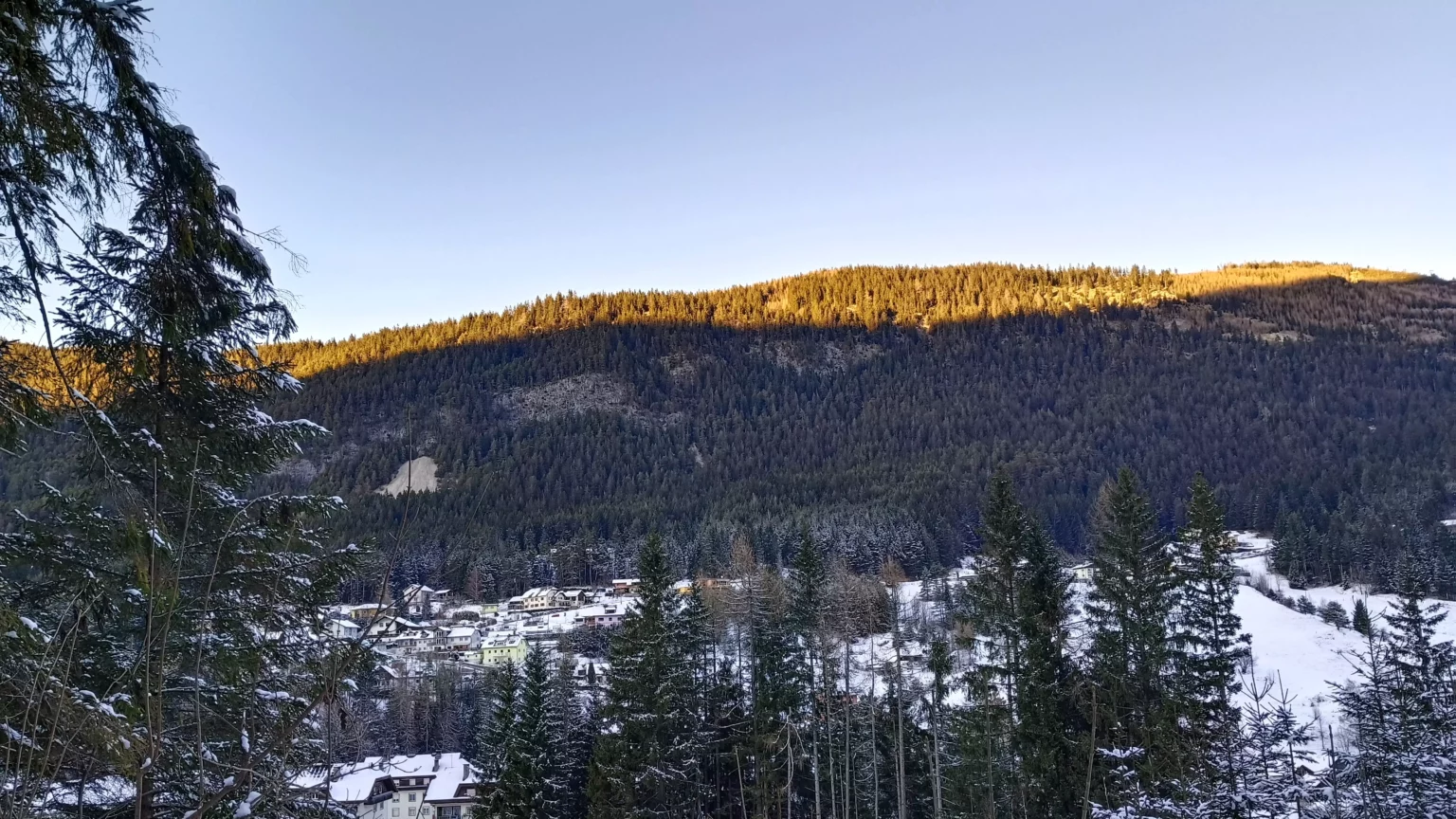 Ein Bild auf 5min.at zeigt den winterlichen Sonnenuntergang im Hochtal Bad Bleiberg in Kärnten. Die Bergspitzen sind golden verfärbt, das Tal liegt bereits im Schatten.