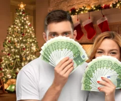 Bild auf 5min.at zeigt zwei Personen mit Geldscheinen, im Hintergrund ist ein Weihnachtsbaum zu sehen.