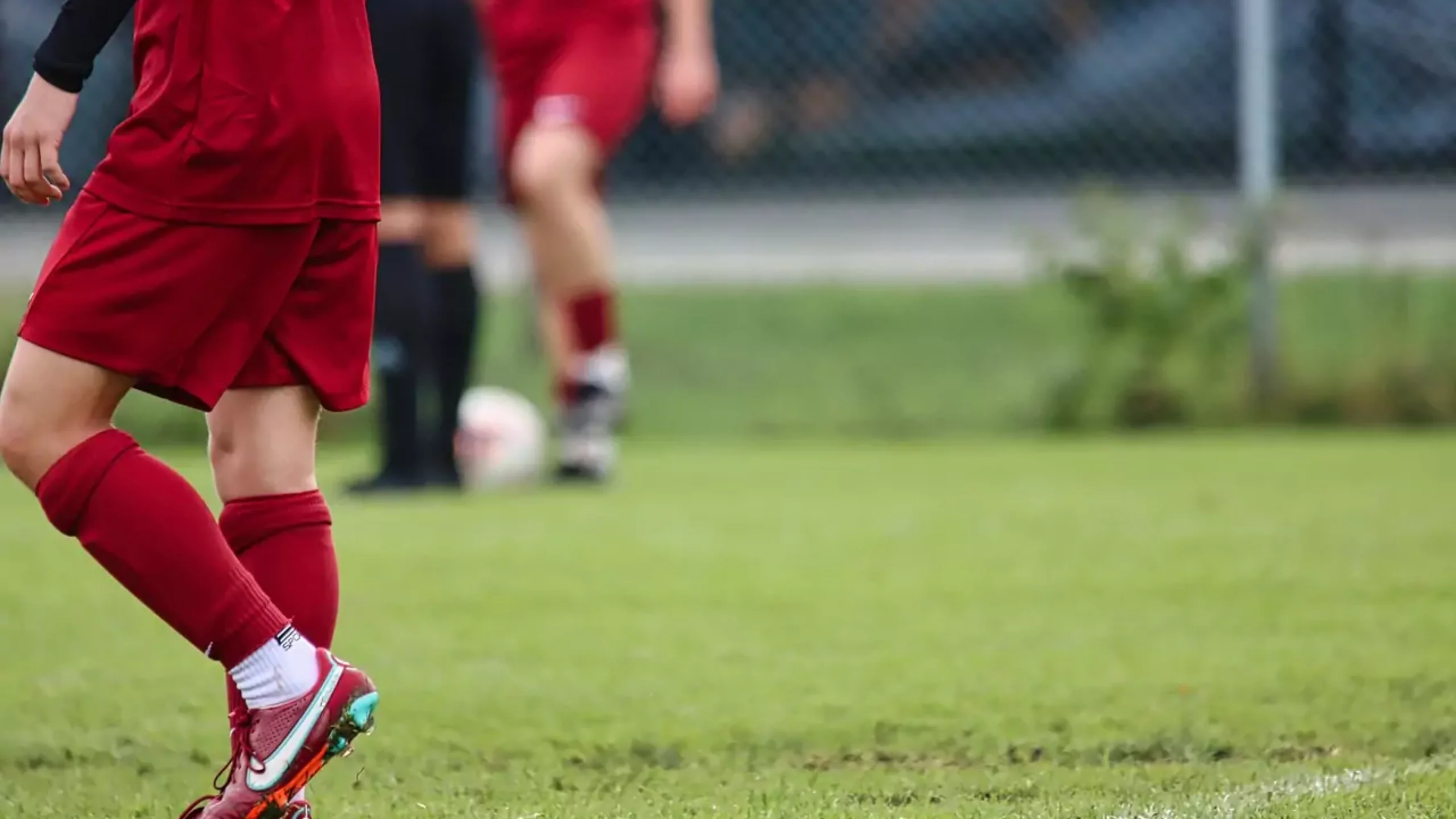 Foto auf 5min.at zeigt zwei unbekannte Fußballspieler in roten Dressen auf dem Spielfeld.