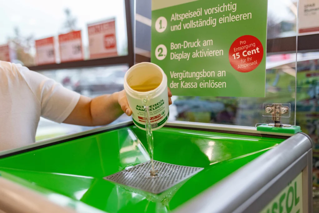 Foto in Beitrag von 5min.at zeigt, wie jemand Altspeiseöl in einen Sammelautomaten entleert.