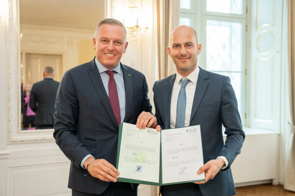 Foto auf 5min.at zeigt zwei Personen in die Kamera lächeln.