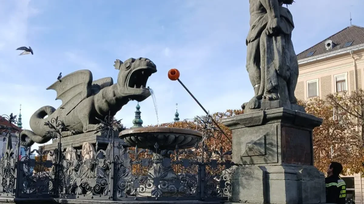 Ein Bild auf 5min.at zeigt, wie die Feuerwehrleute den Kürbis aus dem Maul des Lindwurms holen.