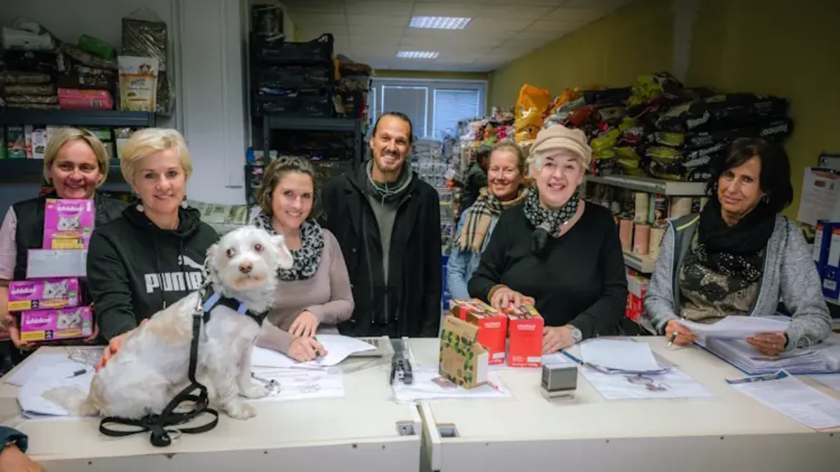 Ein Bild auf 5min.at zeigt Stadtrat Sascha Jabali Adeh mit dem "Tiertafel"-Team. Einige Frauen halten Futterspenden hoch. Auch ein Hund sitzt auf dem Tisch.