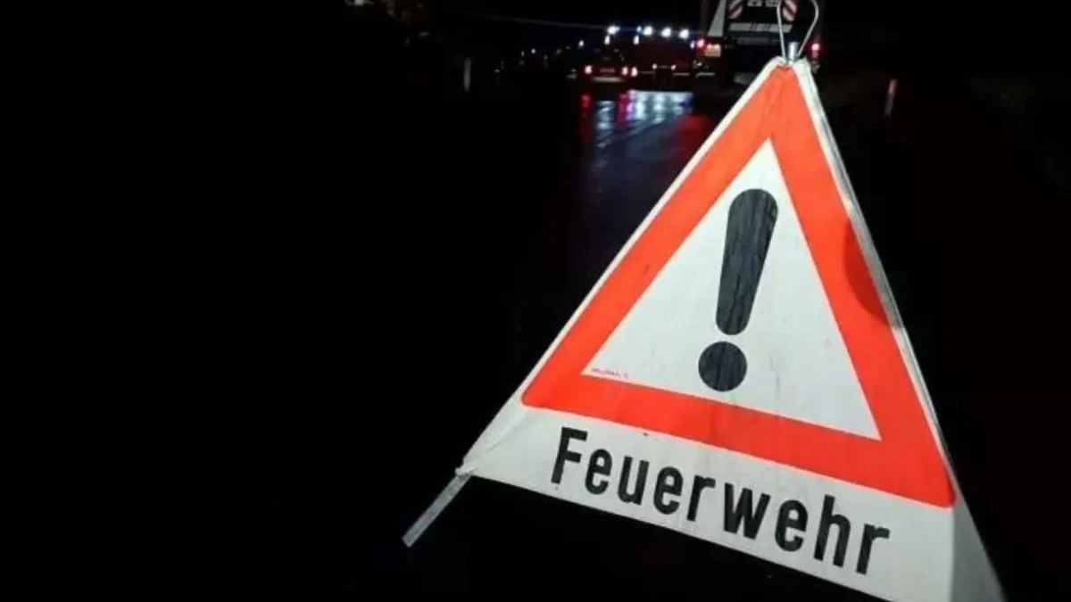 Foto in Beitrag von 5min.at zeigt eine Feuerwehrtafel und dahinter im Hintergrund in der Nacht die Einsatzkräfte.