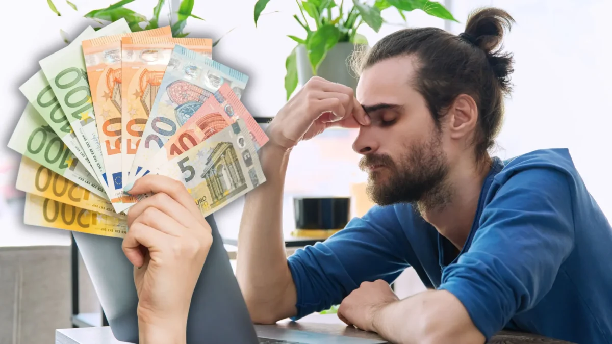 Foto in Beitrag von 5min.at zeigt einen Mann, der verzweifelt vor einem Laptop sitzt und eine Hand mit Geld.