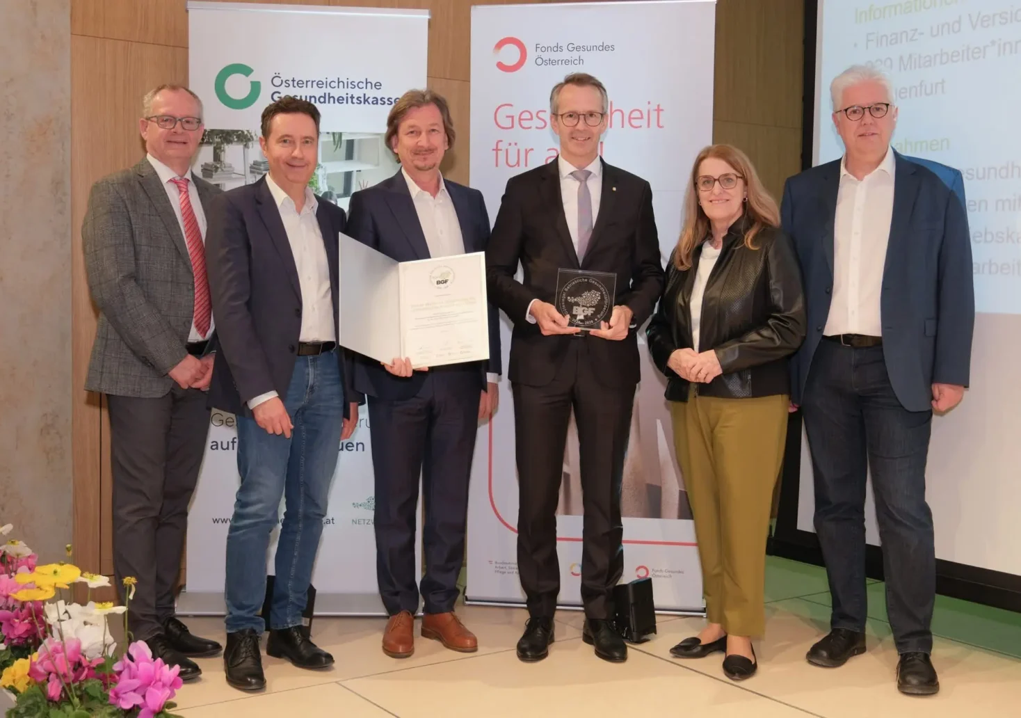 Das Bild zeigt Klaus Ropin – Leiter Fonds Gesundes Österreich (FGÖ); Georg Steiner - Vorsitzender des Landesstellenausschusses Kärnten der Österreichischen Gesundheitskasse; Klaus Werdinig - Personalentwickler; Ferdinand Bucher – Landesdirektor; Ulrike Königsberger-Ludwig – Staatssekretärin im BM für Arbeit, Soziales, Gesundheit und Pflege; Andreas Huss – stv. Obmann der Österreichischen Gesundheitskasse auf 5min.at.